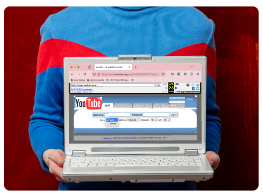 Person holding a laptop with a YouTube screenshot from 2005