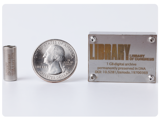 A one gigabyte synthetic DNA storage vial encoded with digital copies of Library collection items is displayed alongside a quarter and the box in which the vial will be encased.