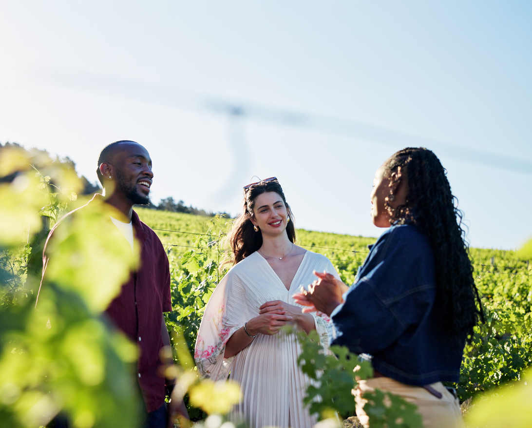 Three people talking in a green field, representing agritourism and rural business opportunities.