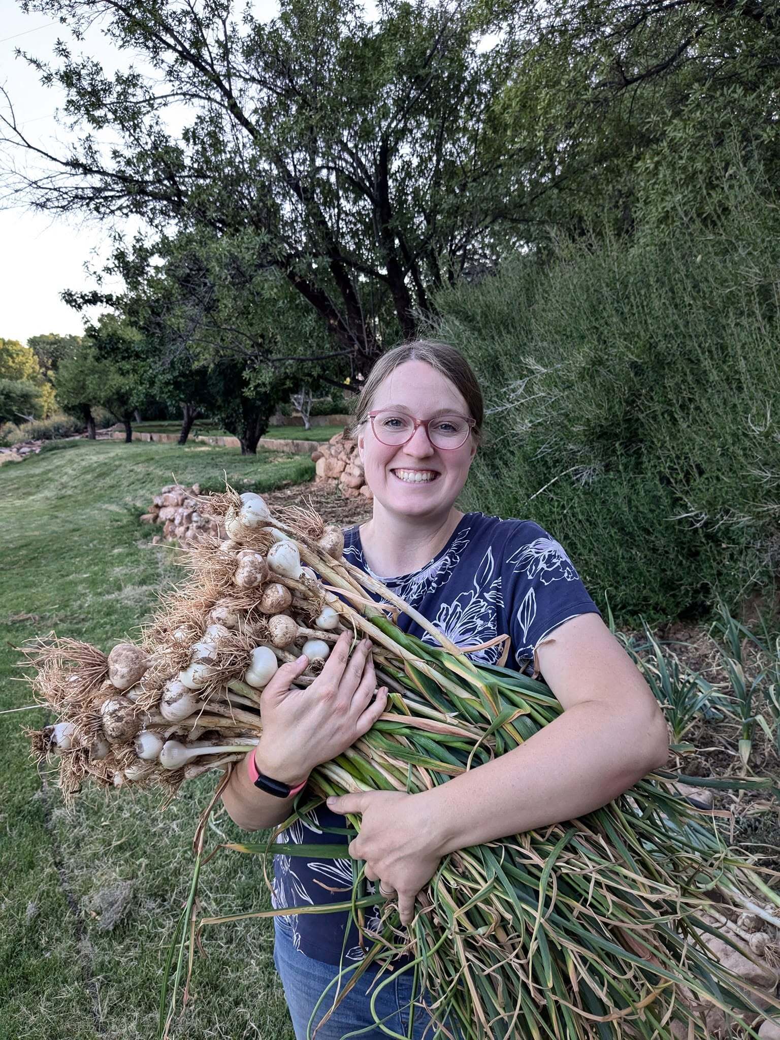 Jessie holding a large harvest of onions from her farm.