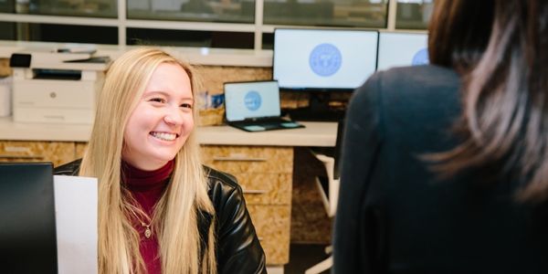 Woman with blonde hair smiling at a coworking member at the front desk