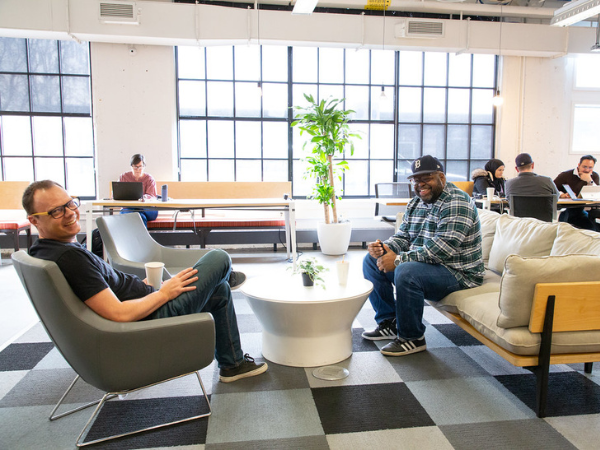Two people sitting in an office, smiling at a camera