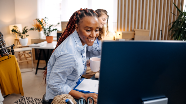 A person smiles while looking at a computer screen
