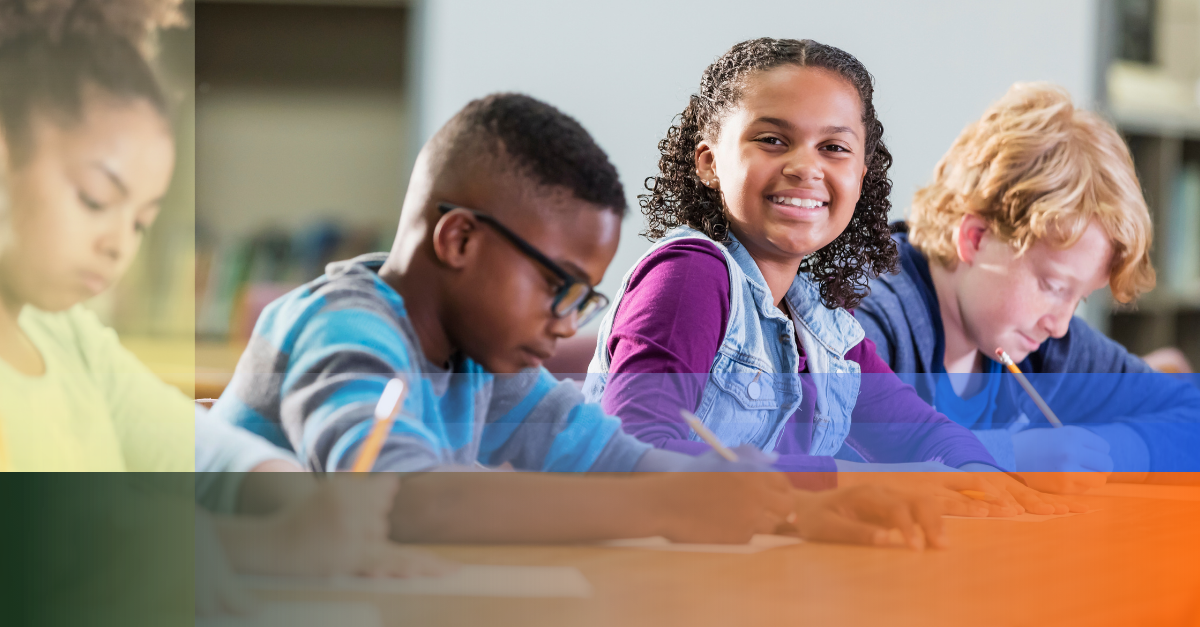 Photo of elementary school children writing while sitting at desks in classroom