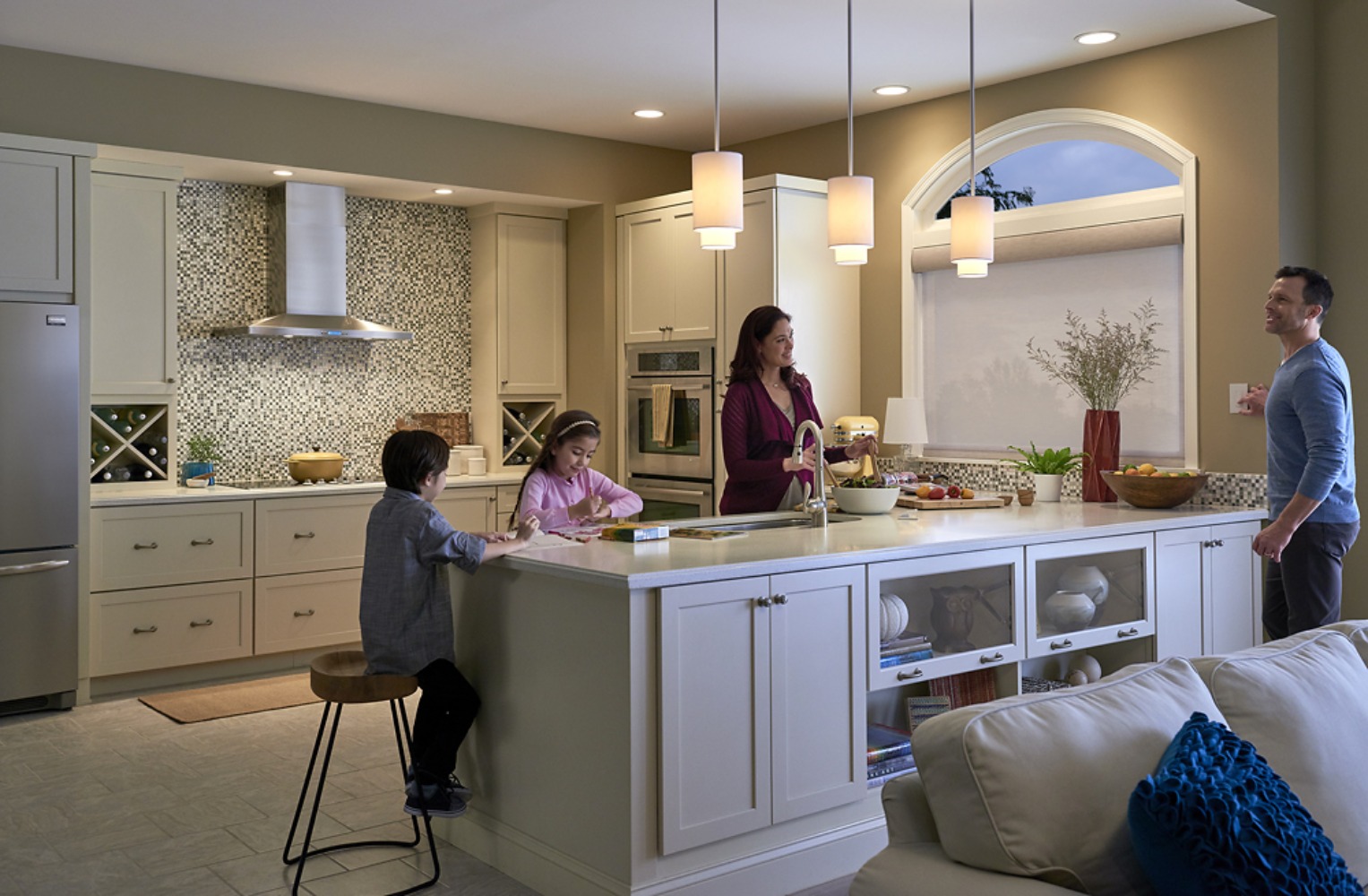Family gathered in kitchen with warm Lutron lighting at dusk
